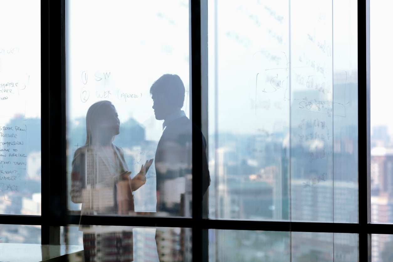  
Two people behind glass wall having conversation
