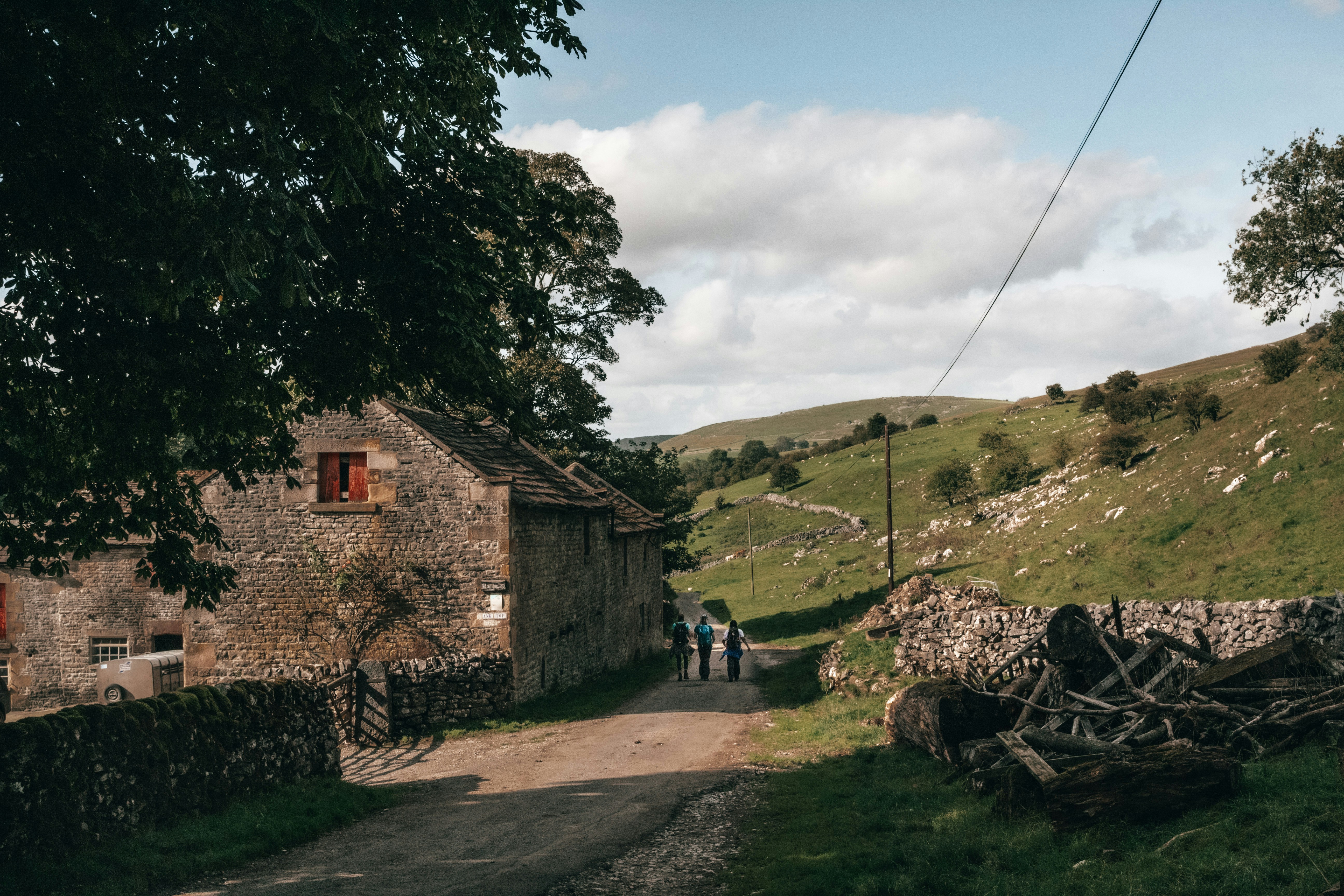 People walking down path next to old farm building