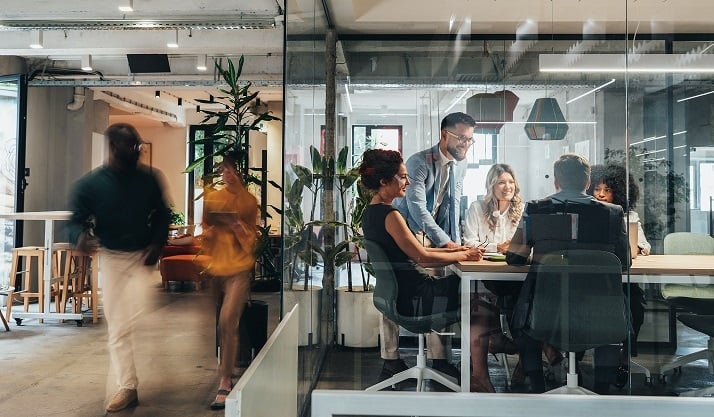 People in meeting room in busy office