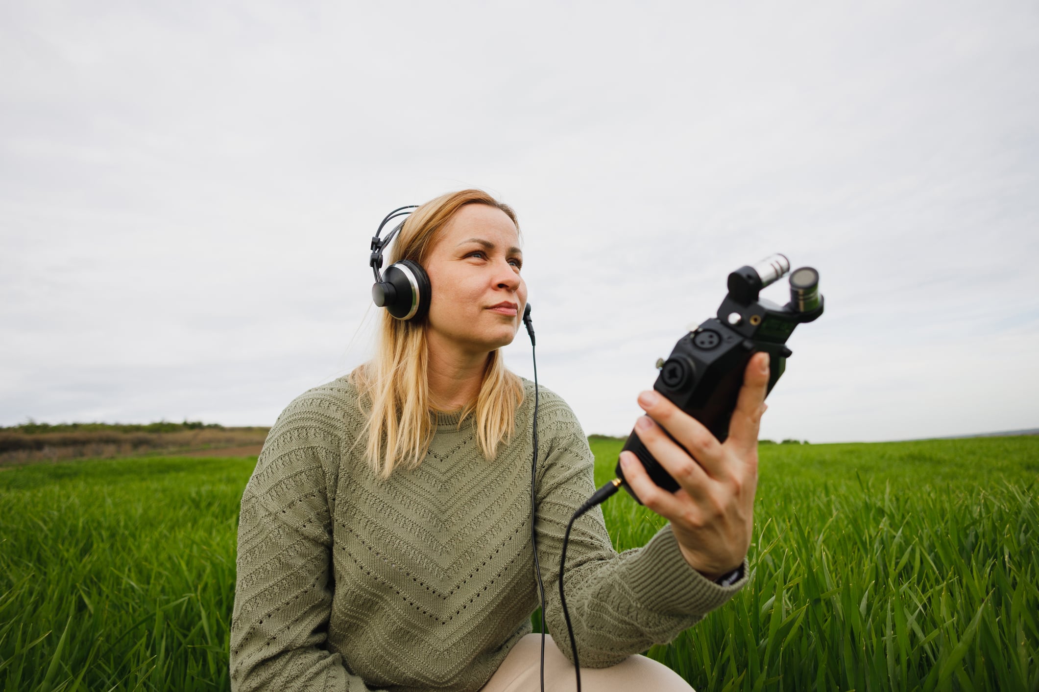  
Women sitting in field with listening device in hand
